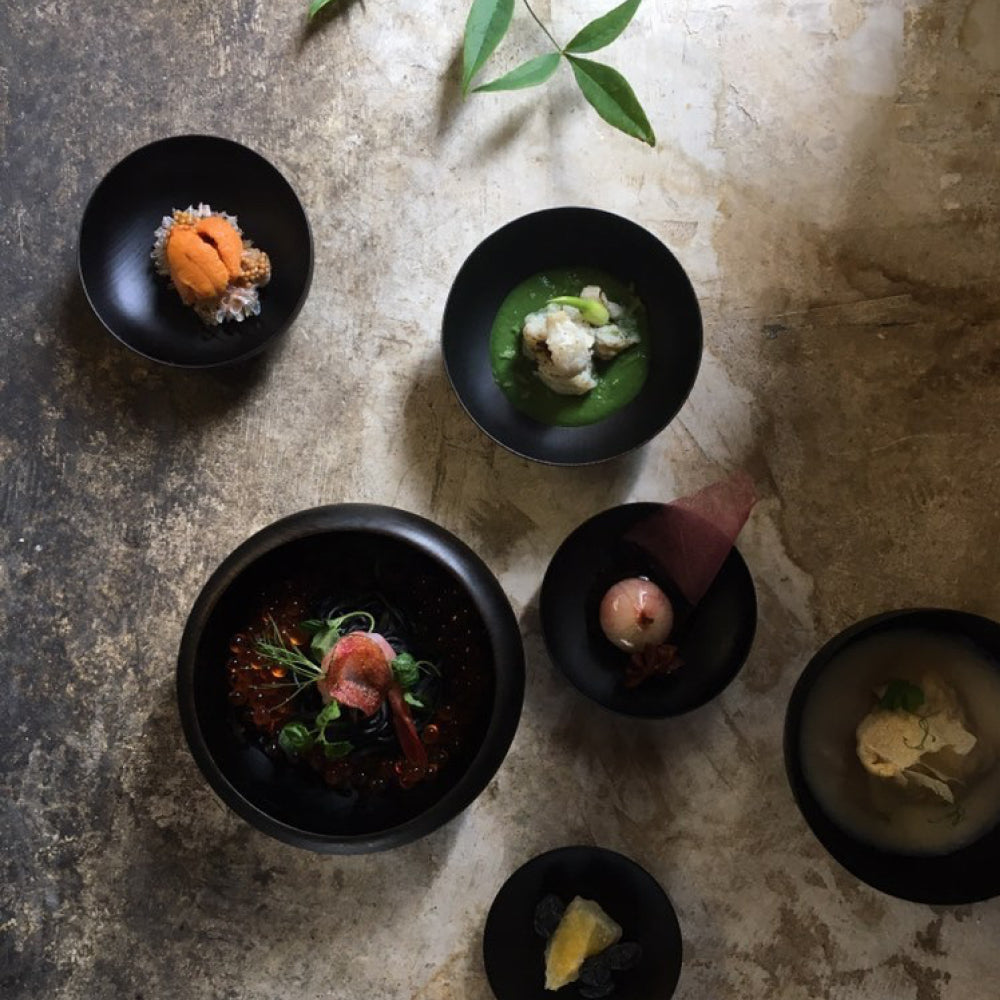 Collection of oryoki bowls with seafood and soup inside them